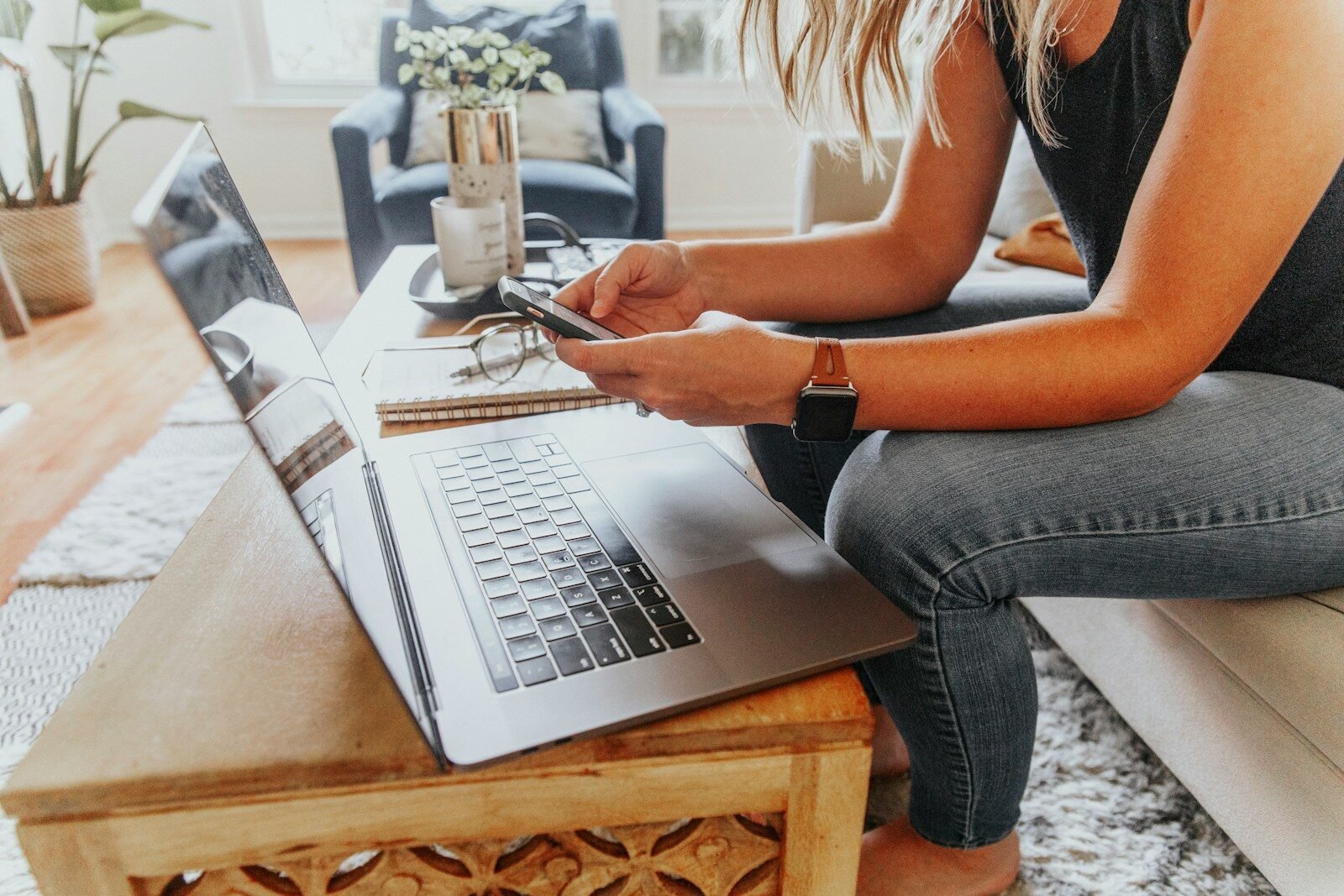 woman in black tank top and blue denim jeans sitting on chair using macbook pro